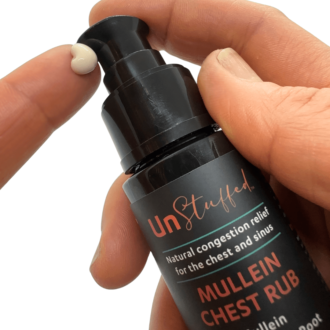 Hand holding a bottle of UnStuffed Mullein Chest Rub against a white background